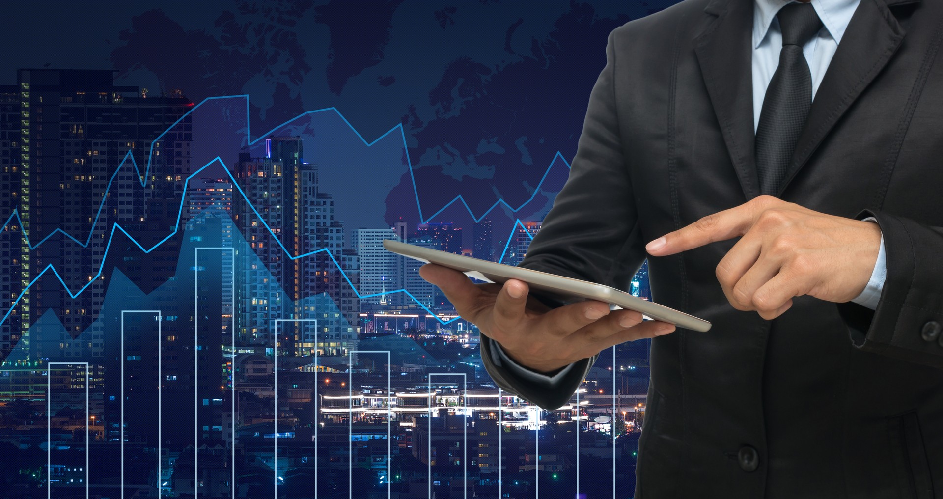 businessman using the tablet on Trading graph on the cityscape at night and world map background,Business financial concept